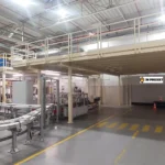 Antresola stalowa na słupach w hali produkcyjnej z barierkami nad ciągiem komunikacyjnym