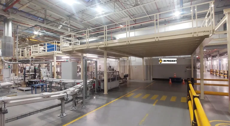 Antresola stalowa na słupach w hali produkcyjnej z barierkami nad ciągiem komunikacyjnym