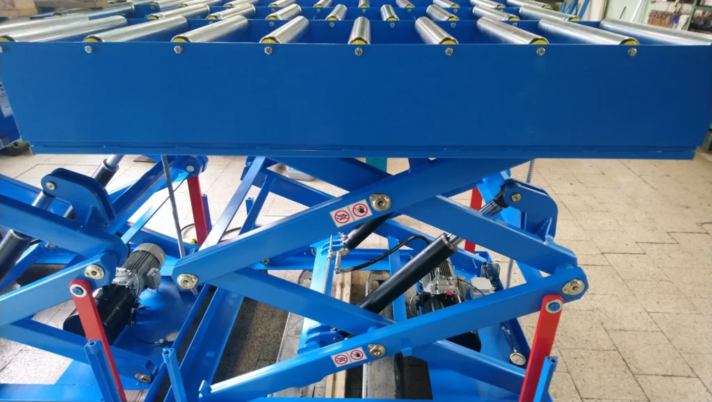 podnośnik-nożycowy-z-zasilaczem-hydraulicznym-produkcji-jnprojekt-z platformą-wyposażoną-w-rolki-transportowe-interroll.