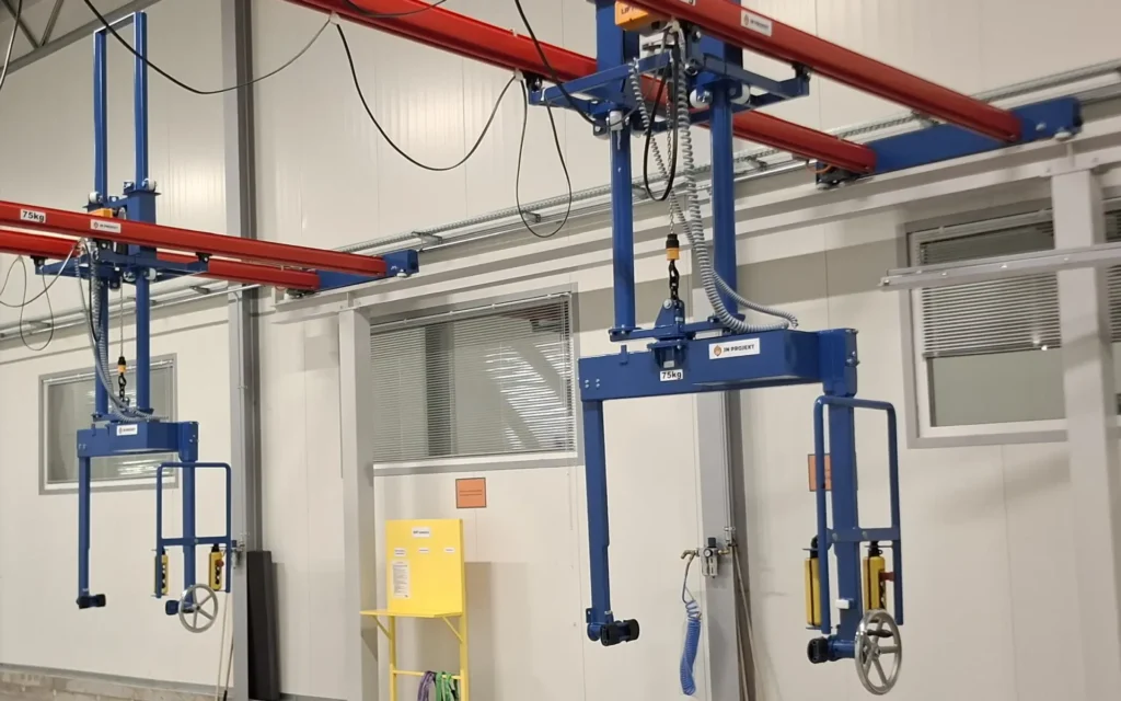 Suwnica natorowa dwudźwigarowa z manipulatorem z rozsuwanymi ramionami i obrotem oraz rolkami prowadzącymi