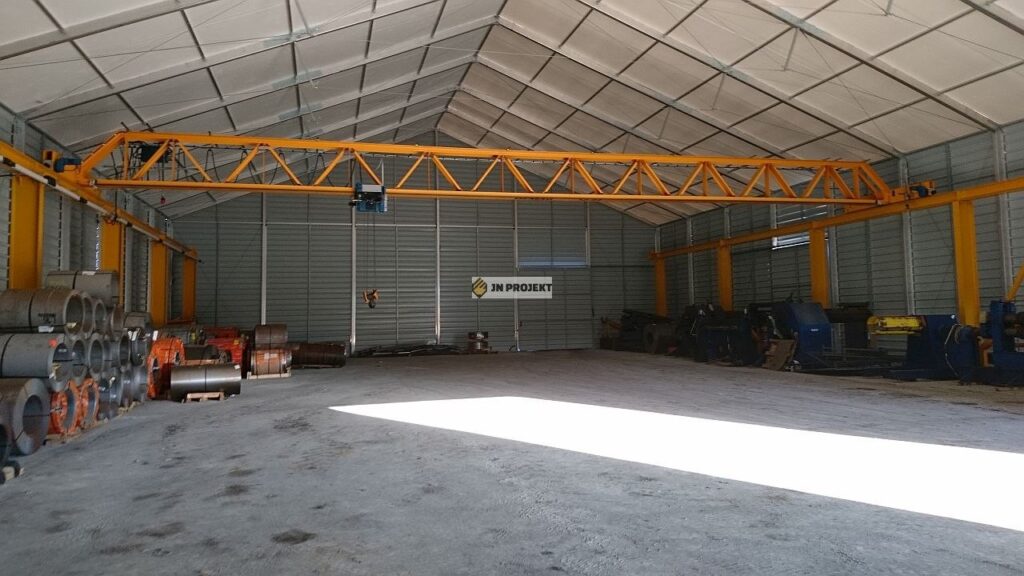 Jednodźwigarowa suwnica natorowa z dźwigarem kratowym i wciągarką linową w hali namiotowej