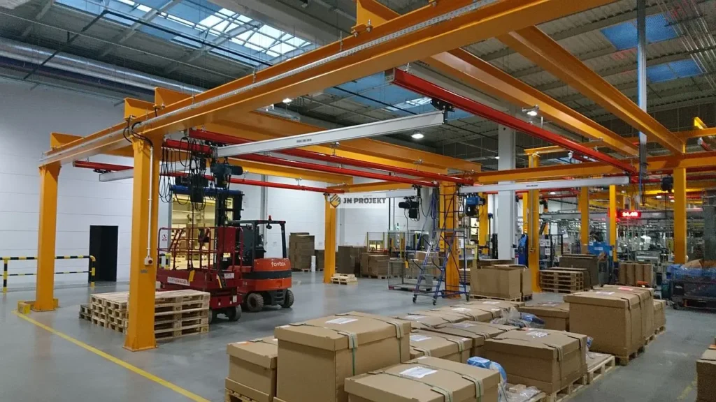 Aluminiowe modułowe suwnice z wciągnikami łańcuchowymi nad stanowiskami kompletacji detali