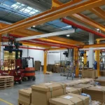 Aluminiowe modułowe suwnice z wciągnikami łańcuchowymi nad stanowiskami kompletacji detali