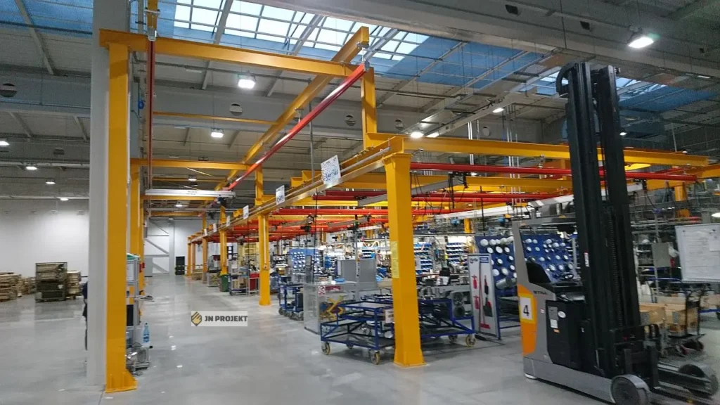 Aluminiowe podwieszane suwnice modułowe z wciągnikami łańcuchowymi nad stanowiskami montażowymi