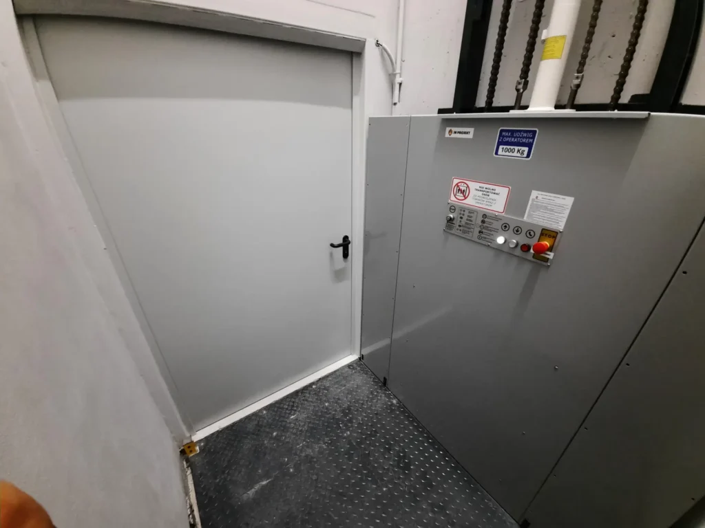 Podnośnik towarowy z siłownikiem hydraulicznym i układem sterowania do transportu między dwoma poziomami