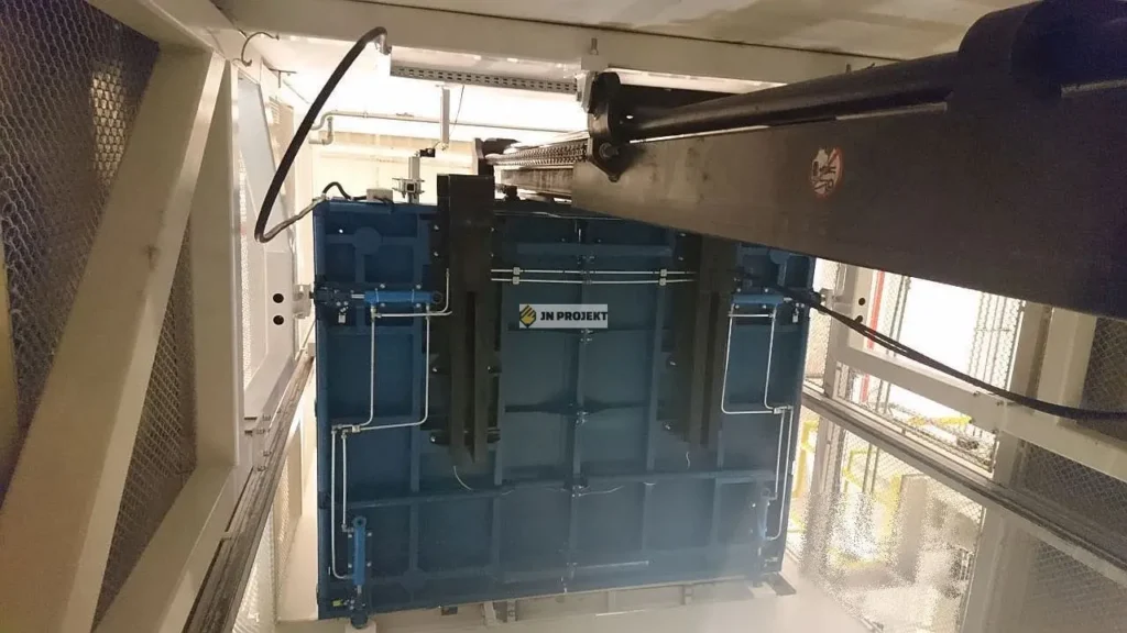 Widok spod platformy towarowej z masztem nośnym i instalacją hydrauliczną