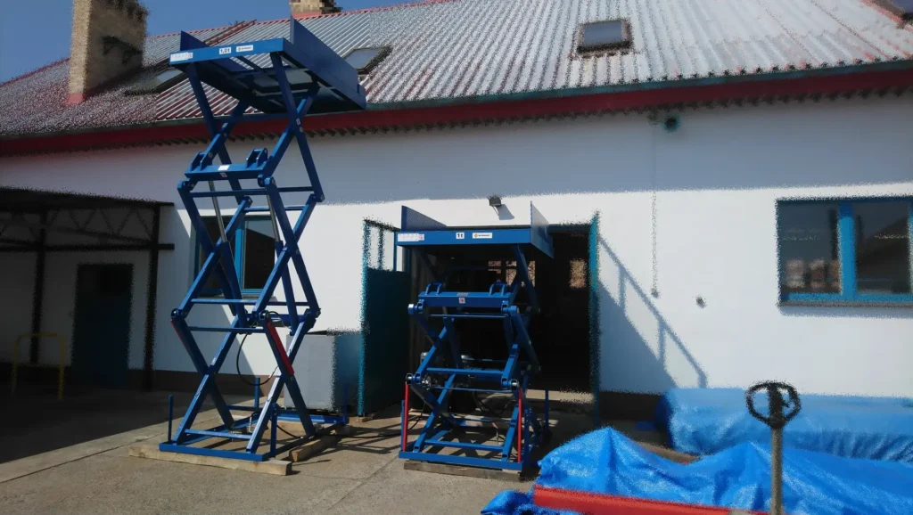 Dwa trzynożycowe podesty hydrauliczne podczas testów jeden w górnym położeniu drugi na podporach serwisowych
