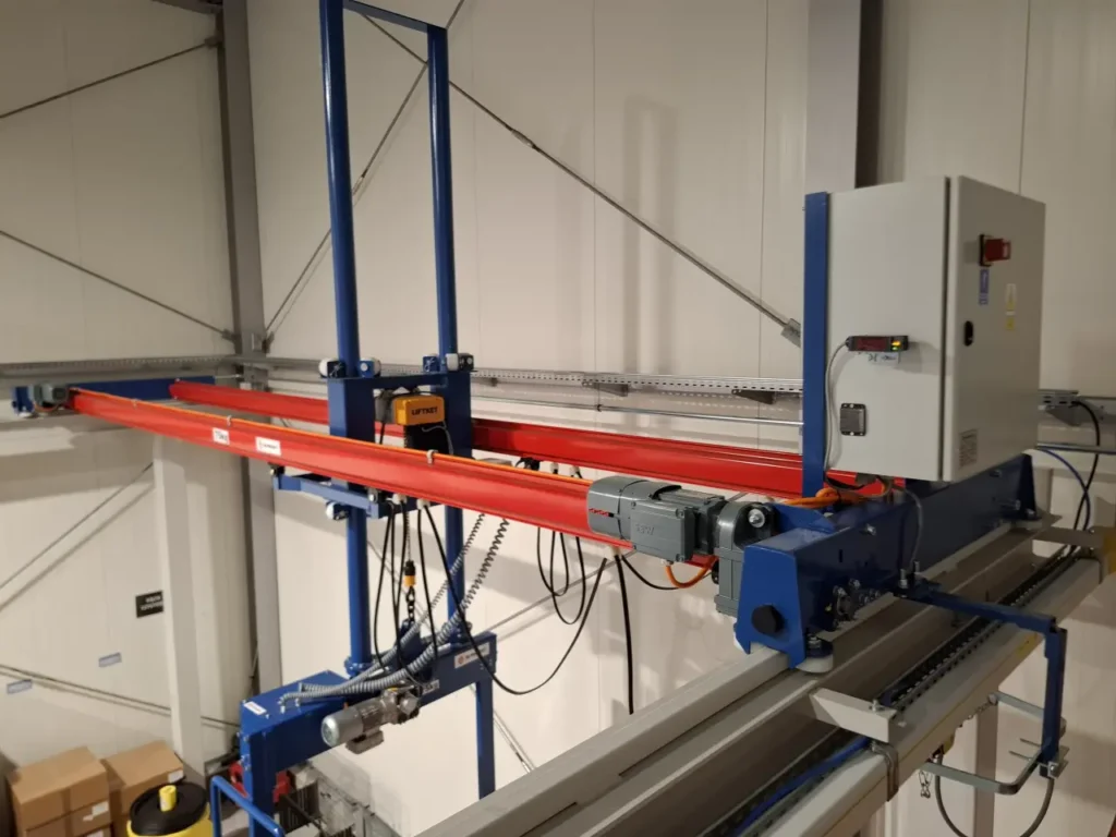 Dwudźwigarowa suwnica natorowa z manipulatorem i sztywnym prowadzeniem ładunku w hali montażowej