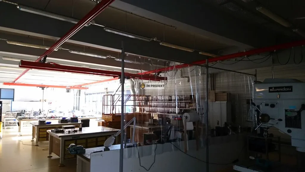 Czerwone suwnice modułowe z wciągnikami łańcuchowymi podwieszone do stropu hali montażowej