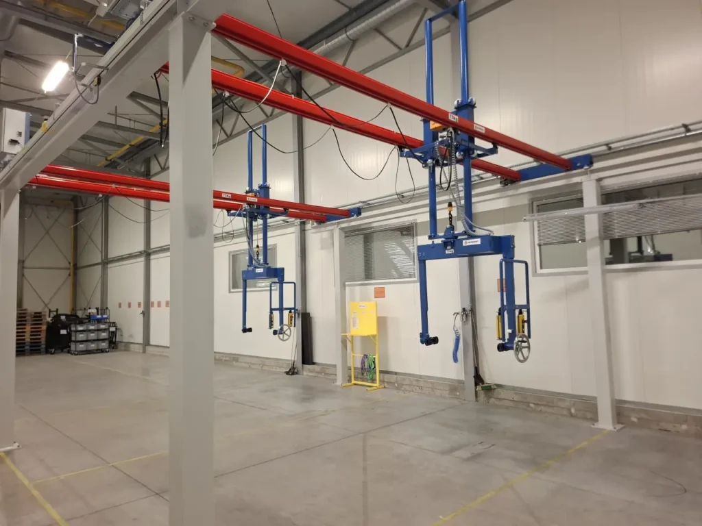 Suwnice natorowe technologiczne z manipulatorami i panelami sterowania na estakadzie